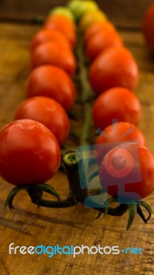 Cherry Tomatoes On Display On Wooden Chopping Board And Wooden Table Stock Photo