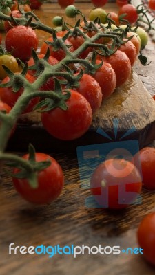 Cherry Tomatoes On Display On Wooden Chopping Board And Wooden Table Stock Photo