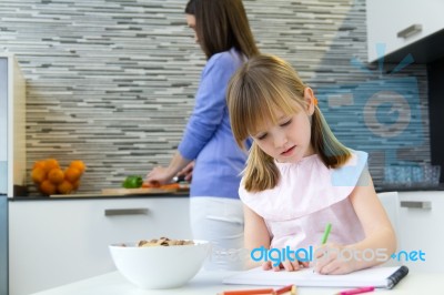 Child Drawing With Crayons, Sitting At Table In Kitchen At Home Stock Photo