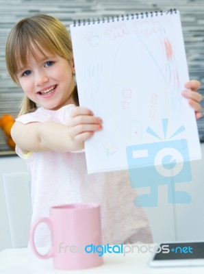 Child Drawing With Crayons, Sitting At Table In Kitchen At Home Stock Photo