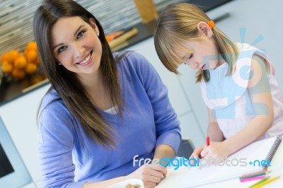 Child Drawing With Crayons With Her Mom At Home Stock Photo