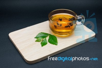 Clear Glass Of Tea And Tea Leaves On Wooden Plate Isolated On Bl… Stock Photo