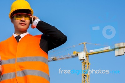 Close Up Young Engineer In Orange Shirt Stands Talking On A Mobi… Stock Photo