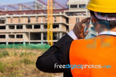 Close Up Young Engineer Wearing A Orange Shirt Stands Talking On… Stock Photo