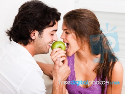 Closeup Of Young Couple Biting Green Apple Stock Photo