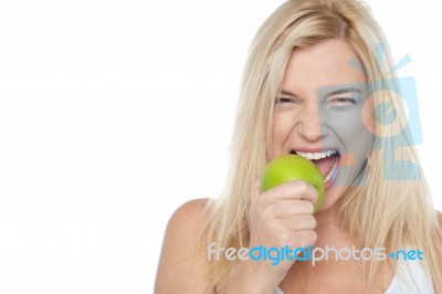 Closeup Shot Of A Blonde Woman Biting An Apple Stock Photo