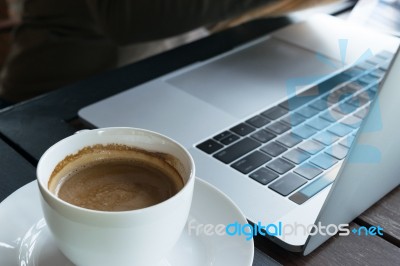 Coffee And Blur Laptop On Table Wood Background In Cafe Stock Photo