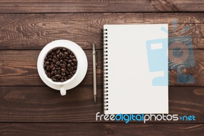 Coffee Beans In Cup And Book Blank Page On Wood Table Stock Photo