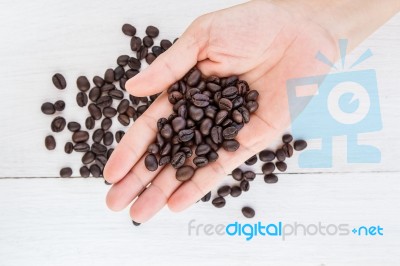 Coffee Beans In Hand Against Coffee Background Stock Photo