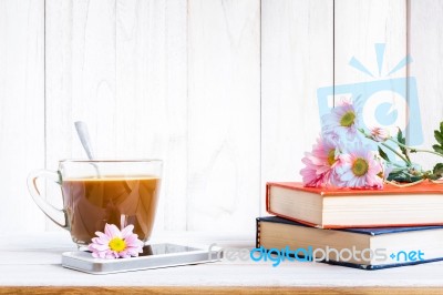 Coffee Cup And Books Or Journal With Flowers Arranged On A Neutral White Painted Desk Stock Photo