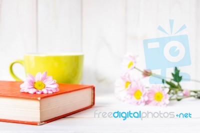 Coffee Cup And Books Or Journal With Flowers Arranged On A Neutral White Painted Desk Stock Photo