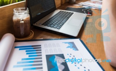 Coffee Cup  On A Table With Laptob And Graph Finance Diagram In Stock Photo