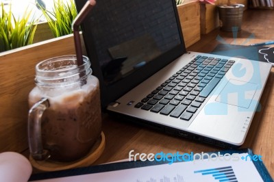 Coffee Cup  On A Table With Laptob And Graph Finance Diagram In Stock Photo