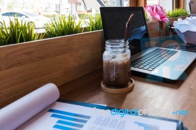 Coffee Cup  On A Table With Laptob And Graph Finance Diagram In Stock Photo