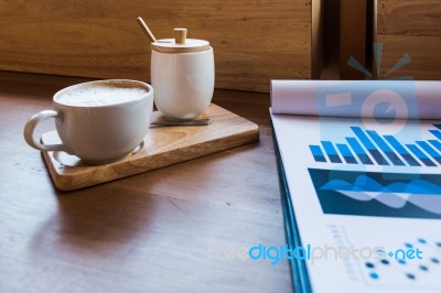 Coffee Cup  On A Table With Laptob And Graph Finance Diagram In Stock Photo