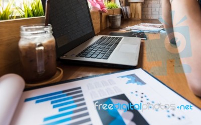 Coffee Cup  On A Table With Laptob And Graph Finance Diagram In Stock Photo