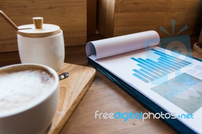 Coffee Cup  On A Table With Laptob And Graph Finance Diagram In Stock Photo