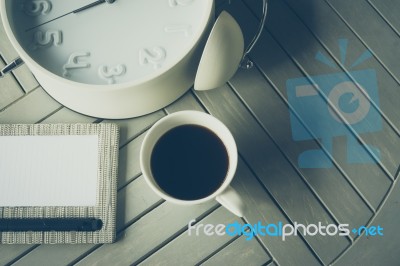 Coffee, Notebook And Alarm Clock On Wooden Table Stock Photo