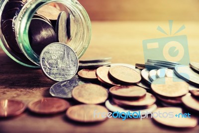 Coins Spilling Out Of A Glass Bottle Stock Photo