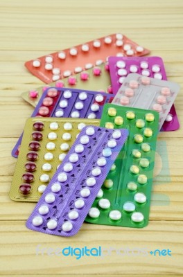 Colorful Oral Contraceptive Pill Strips On Pine Wood Table Stock Photo