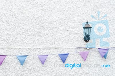 Colorful Party Flags Bunting Hanging On White Wall Background With Wall Lamp Light. Minimal Hipster Style Design Stock Photo