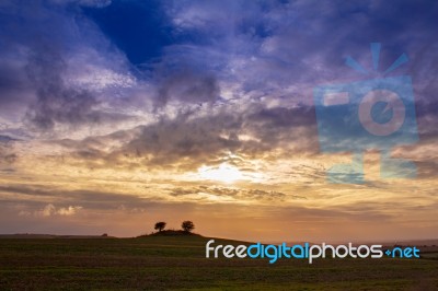 Colourful Cloudy Sky Sunset Behind A Small Hill Stock Photo