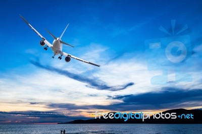 Commercial Airplane Flying Above The Sea At Sunset Stock Photo