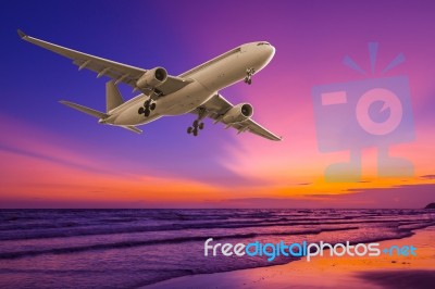 Commercial Airplane Flying Above The Sea At Sunset Stock Photo