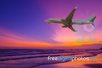 Commercial Airplane Flying Above The Sea At Sunset Stock Photo