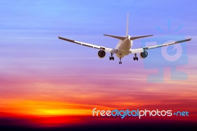 Commercial Airplane Flying At Sunset Stock Photo