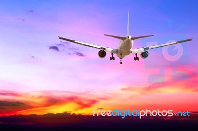 Commercial Airplane Flying At Sunset Stock Photo