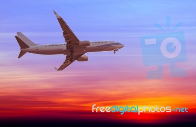 Commercial Airplane Flying At Sunset Stock Photo