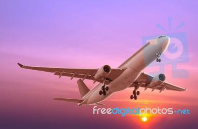 Commercial Airplane Flying At Sunset Stock Photo