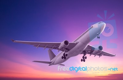 Commercial Airplane Flying At Sunset Stock Photo