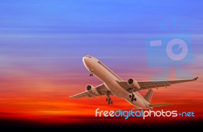 Commercial Airplane Flying At Sunset Stock Photo