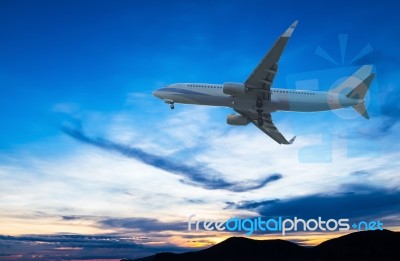 Commercial Airplane Flying At Sunset Stock Photo