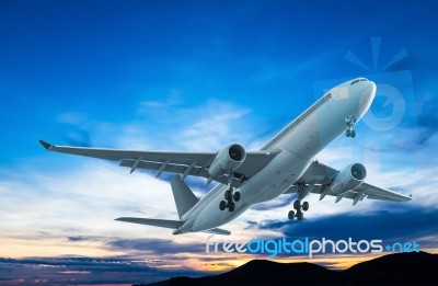 Commercial Airplane Flying At Sunset Stock Photo