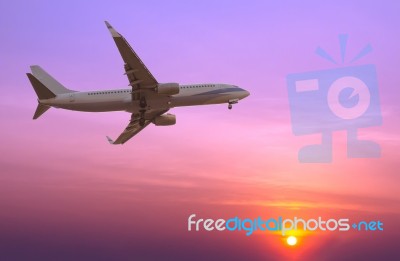 Commercial Airplane Flying At Sunset Stock Photo