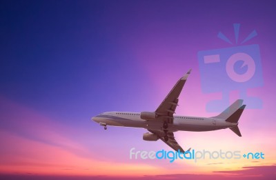 Commercial Airplane Flying At Sunset Stock Photo