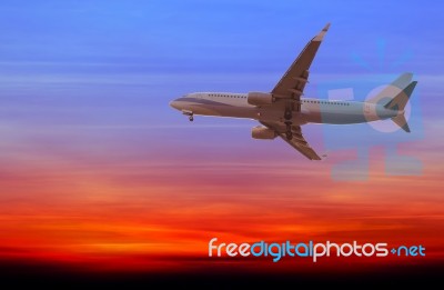 Commercial Airplane Flying At Sunset Stock Photo