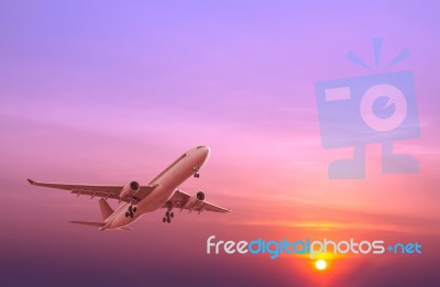 Commercial Airplane Flying At Sunset Stock Photo