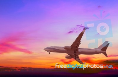 Commercial Airplane Flying At Sunset Stock Photo