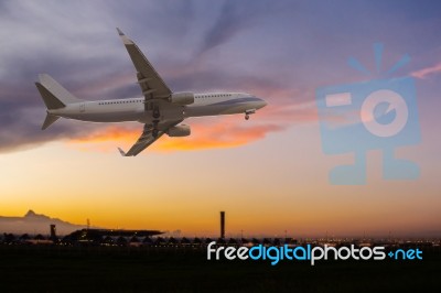 Commercial Airplane Flying Over The Airport At Sunset Stock Photo