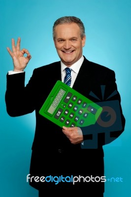 Confident Executive Holding Calculator And Gesturing Okay Sign Stock Photo