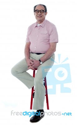 Confident Old Man Resting On Stool Stock Photo