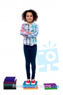 Confident School Child Standing On Books Stock Photo