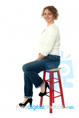 Confident Senior Woman Resting On Stool Stock Photo