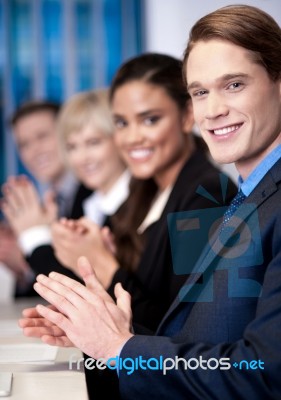 Corporate Team Sitting In A Row And Applauding Stock Photo