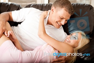 Couple Cuddling On Sofa Stock Photo