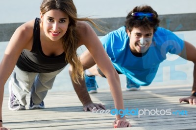 Couple Doing Push Ups Near The Sea Stock Photo